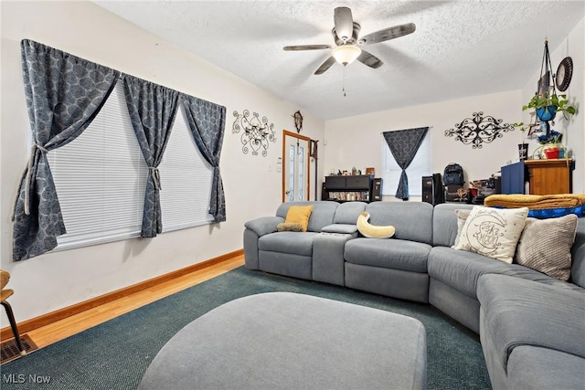 living room with ceiling fan, a textured ceiling, baseboards, and wood finished floors