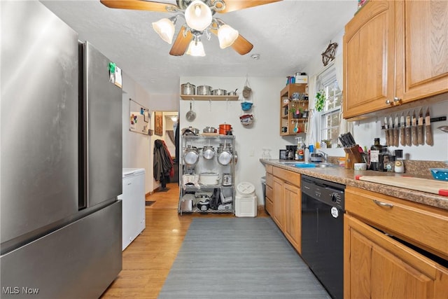 kitchen featuring black dishwasher, freestanding refrigerator, light countertops, light wood-type flooring, and a sink