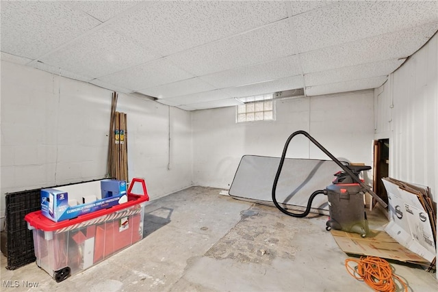 below grade area featuring a paneled ceiling and concrete block wall