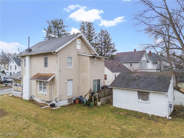 back of property featuring an outbuilding, a lawn, and a residential view