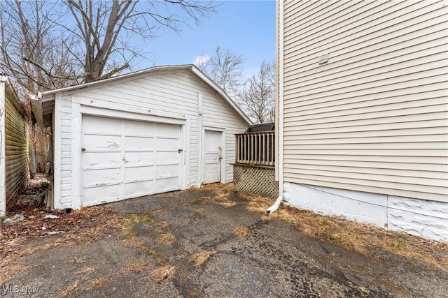 exterior space with aphalt driveway, a detached garage, and an outdoor structure