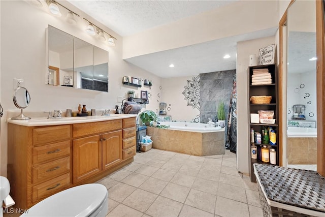 full bath featuring a garden tub, toilet, a sink, a textured ceiling, and tile patterned floors