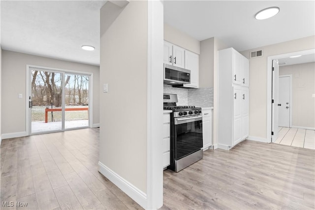 kitchen featuring stainless steel appliances, visible vents, backsplash, light wood-style floors, and white cabinets