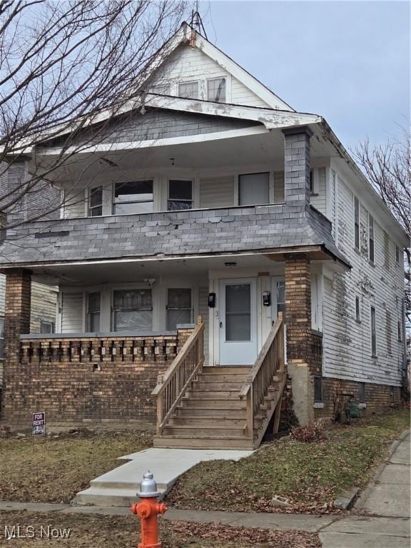 view of front of home featuring covered porch, brick siding, and a balcony