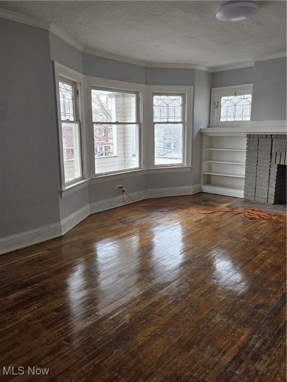 unfurnished living room featuring crown molding, hardwood / wood-style floors, a brick fireplace, and baseboards