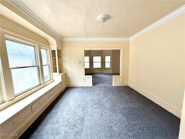 unfurnished room featuring a healthy amount of sunlight, dark carpet, and ornamental molding