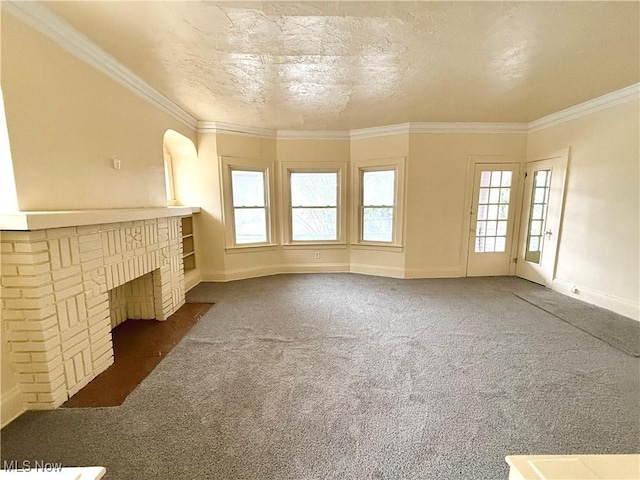 unfurnished living room featuring a textured ceiling, carpet floors, a fireplace, baseboards, and crown molding