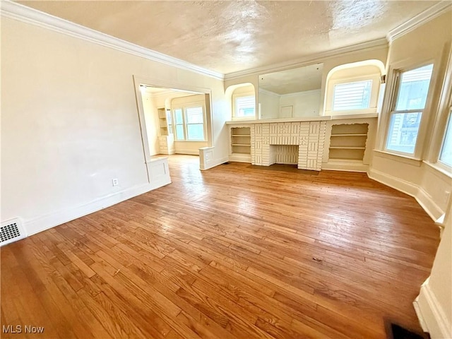 interior space featuring crown molding, visible vents, a textured ceiling, light wood-type flooring, and baseboards