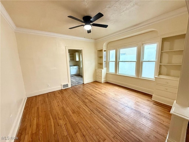 unfurnished bedroom featuring ceiling fan, hardwood / wood-style flooring, visible vents, baseboards, and ornamental molding