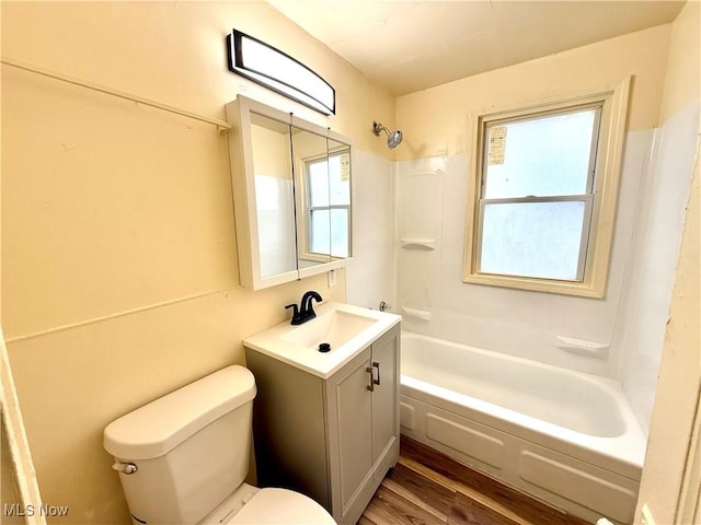 bathroom with toilet, washtub / shower combination, wood finished floors, and vanity