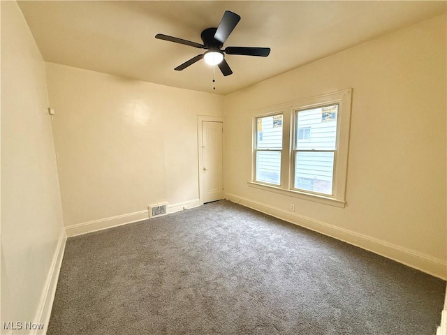 unfurnished room with ceiling fan, dark colored carpet, visible vents, and baseboards