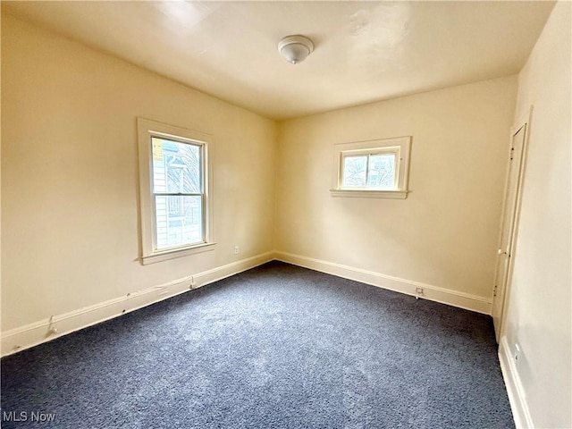 spare room with dark colored carpet and baseboards