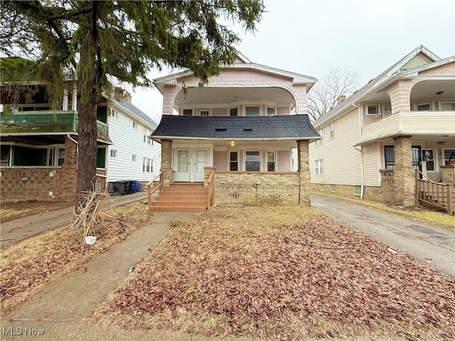 view of front of property featuring a porch, a shingled roof, and brick siding