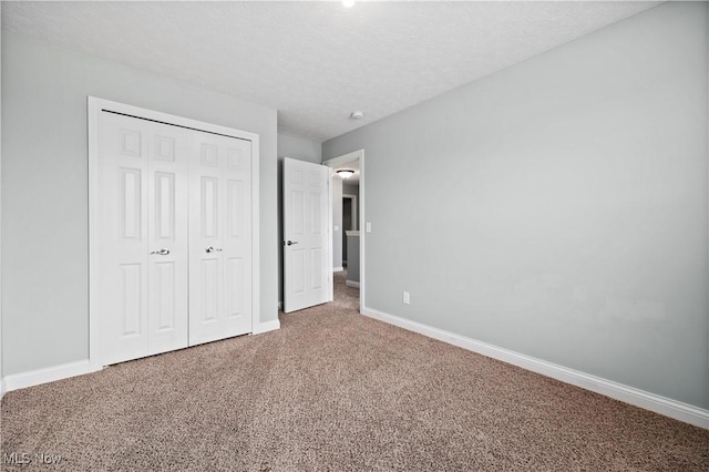 unfurnished bedroom with carpet, a closet, a textured ceiling, and baseboards