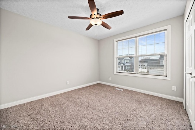 carpeted empty room with a ceiling fan, visible vents, baseboards, and a textured ceiling