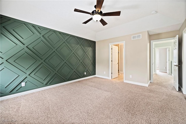 unfurnished room with baseboards, visible vents, light colored carpet, ceiling fan, and an accent wall