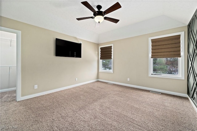 empty room featuring lofted ceiling, carpet, a ceiling fan, and baseboards