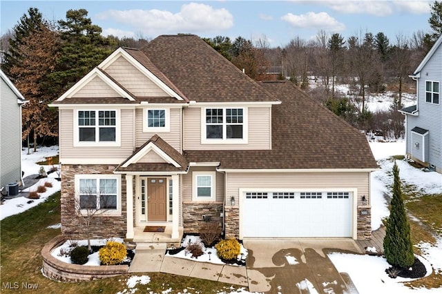 view of front of property featuring a garage, stone siding, a shingled roof, and central AC