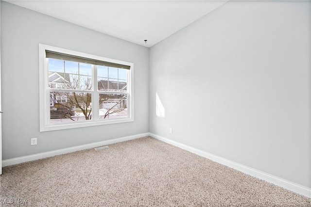 empty room featuring carpet floors, visible vents, and baseboards