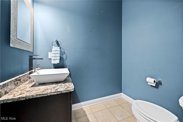 half bathroom featuring toilet, tile patterned flooring, baseboards, and vanity