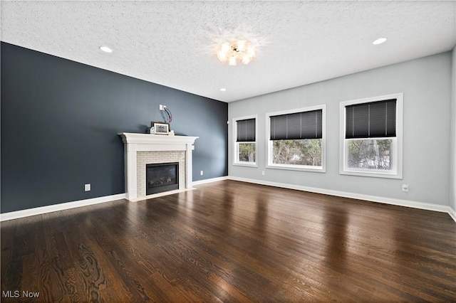 unfurnished living room featuring baseboards, a tiled fireplace, wood finished floors, a textured ceiling, and recessed lighting