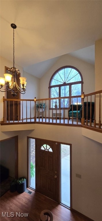 entrance foyer featuring a chandelier, high vaulted ceiling, wood finished floors, and stairs