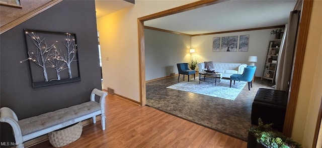 living area featuring crown molding, baseboards, and wood finished floors