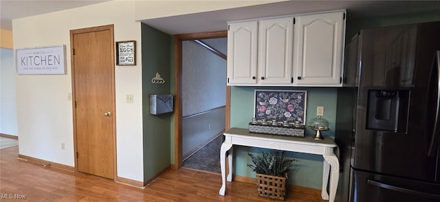 kitchen with light countertops, light wood finished floors, refrigerator with ice dispenser, and white cabinetry