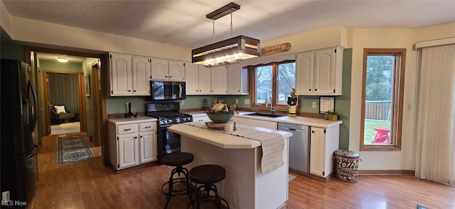 kitchen featuring dark wood-style flooring, light countertops, a sink, and black appliances