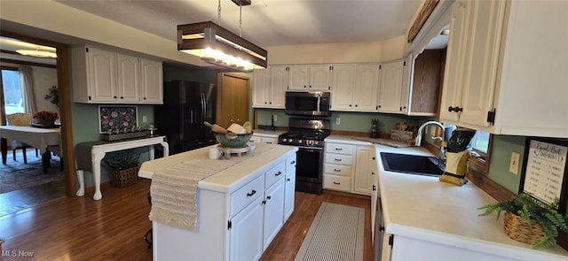 kitchen featuring dark wood-style flooring, a kitchen island, a sink, light countertops, and appliances with stainless steel finishes