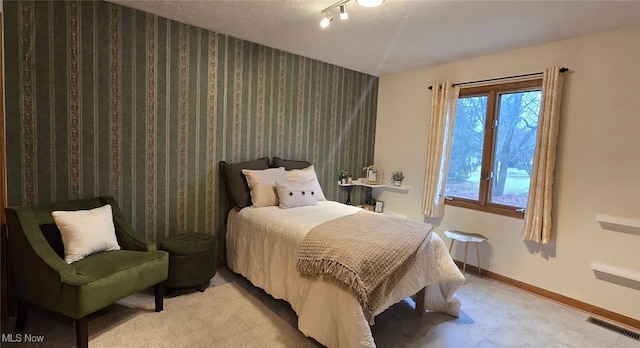 bedroom with a textured ceiling, wallpapered walls, visible vents, and baseboards