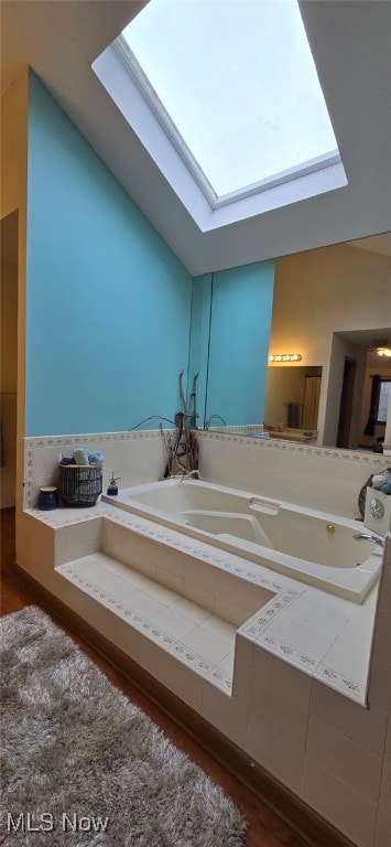 full bathroom with vaulted ceiling with skylight and a bath