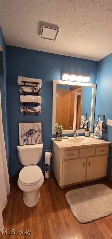 bathroom with visible vents, toilet, a textured ceiling, vanity, and wood finished floors