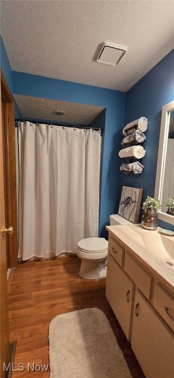 bathroom with visible vents, toilet, wood finished floors, a textured ceiling, and vanity