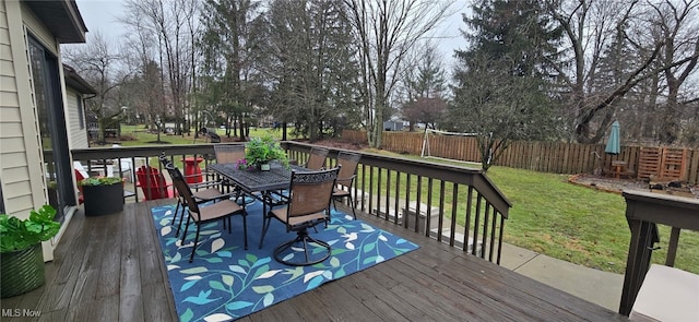 deck featuring outdoor dining area, a lawn, and fence