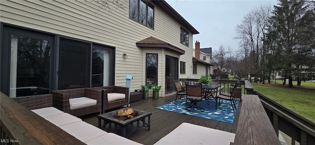 wooden deck featuring outdoor dining space, an outdoor living space with a fire pit, and a lawn