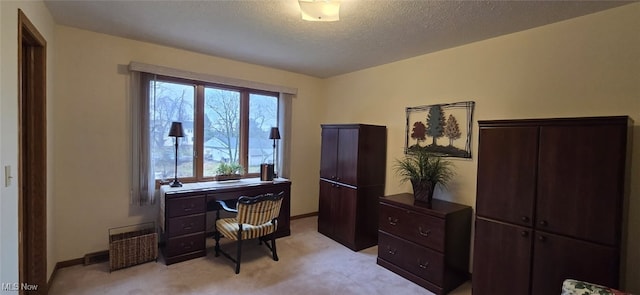 office space with light colored carpet, a textured ceiling, and baseboards