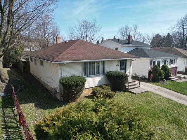 view of front of home with fence, a chimney, and a front lawn