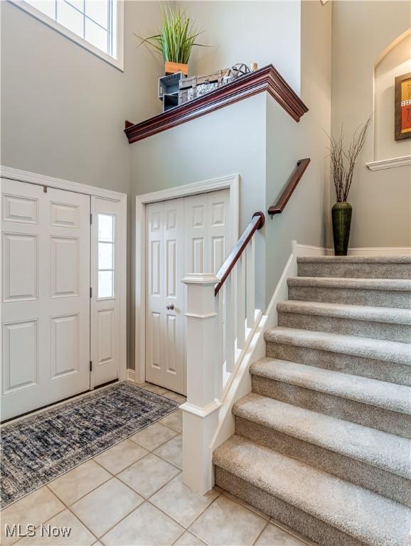 foyer featuring light tile patterned floors, a high ceiling, and stairway