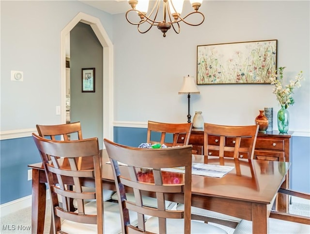 dining space featuring an inviting chandelier, baseboards, and arched walkways