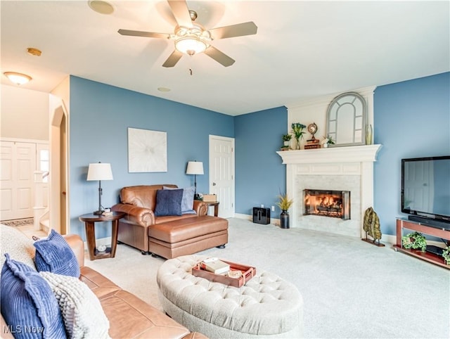 carpeted living room with a lit fireplace, a ceiling fan, and baseboards