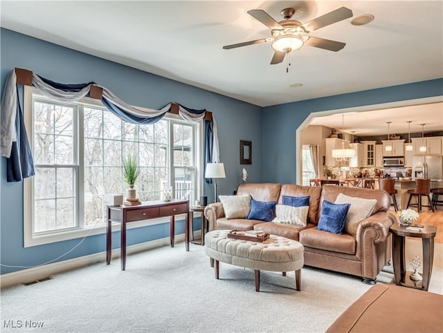 living area with arched walkways, plenty of natural light, baseboards, and ceiling fan