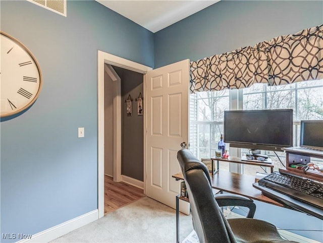 office featuring baseboards, carpet floors, visible vents, and a healthy amount of sunlight