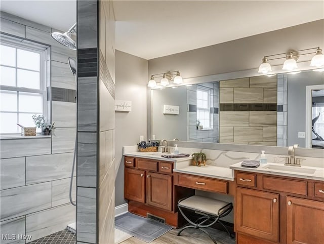 bathroom featuring a walk in shower, double vanity, and a sink