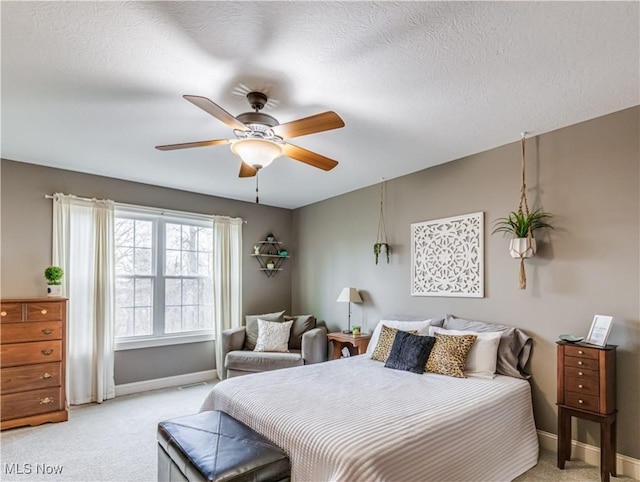 bedroom with a ceiling fan, baseboards, a textured ceiling, and light colored carpet