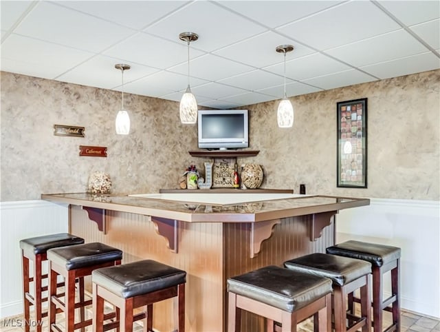 bar with a wainscoted wall, a dry bar, a paneled ceiling, and wallpapered walls