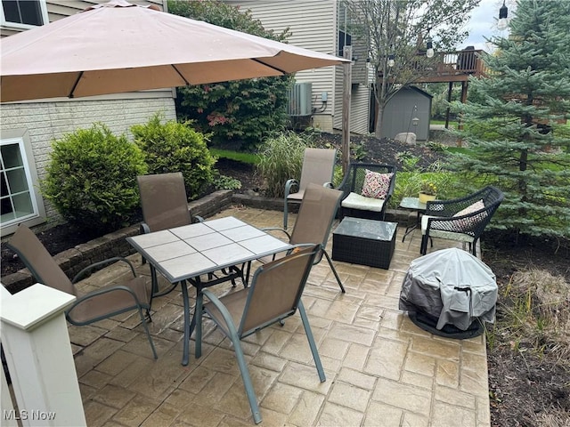 view of patio / terrace featuring an outbuilding, a storage unit, outdoor dining area, and a grill