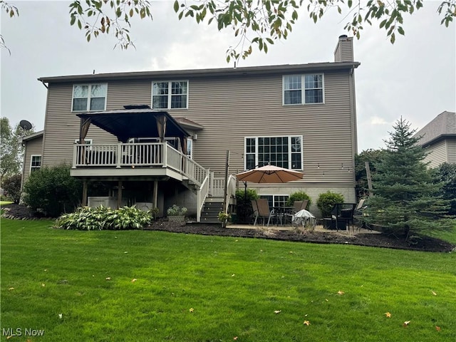 rear view of house with a chimney, a lawn, stairway, a patio area, and a deck