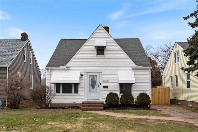 bungalow-style home with a shingled roof, entry steps, a chimney, and a front yard