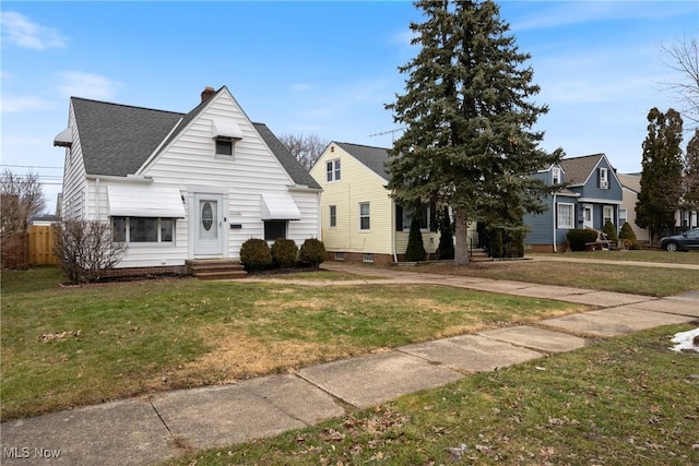 bungalow-style home with entry steps, a shingled roof, a chimney, fence, and a front yard